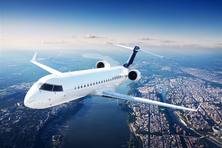 Private jet flying above a city at dusk