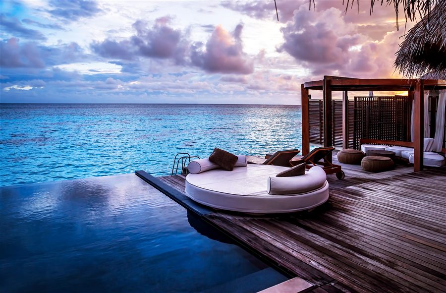 Overwater resort daybed at sunset